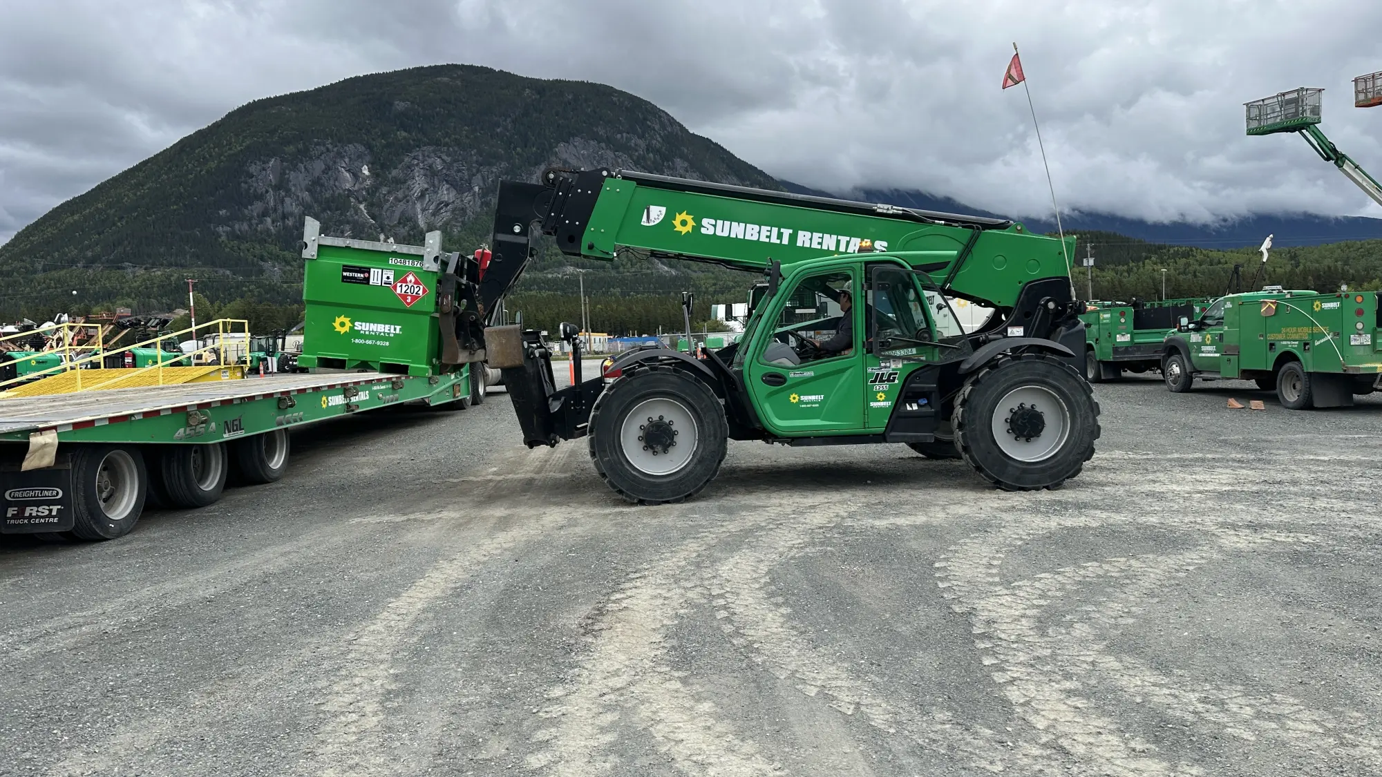 A student operating a telehandler during a hands-on heavy equipment operator training course provided by Karma Training in Northwestern BC. The image shows a green telehandler and other heavy machinery, highlighting Karma Trainings commitment to practical, on-site training.