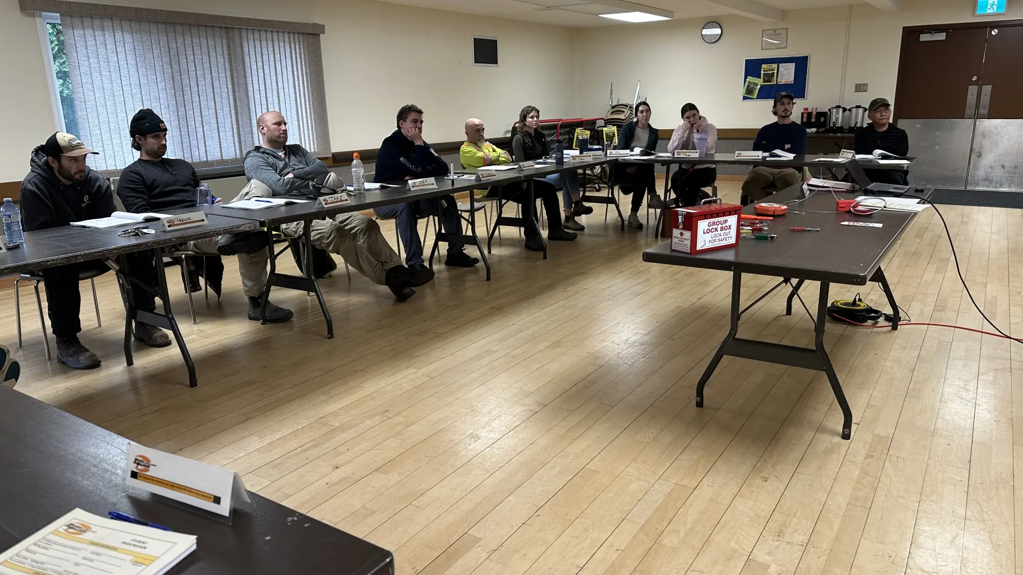 A photograph showing a group of students attentively participating in a safety training session led by Karma Training. The image depicts a classroom setting with participants seated at tables, focused on the instruction. Karma Training, a premier safety training provider in Northwestern BC, delivers this hands-on, practical training.